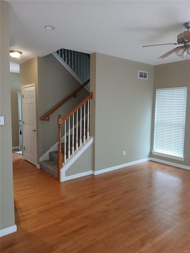 empty room with baseboards, ceiling fan, visible vents, and wood finished floors