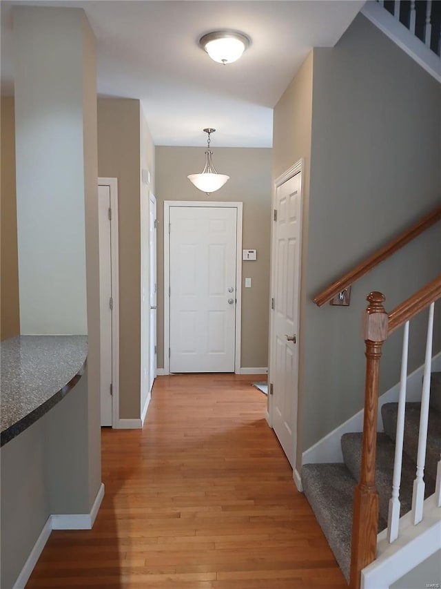 entryway with baseboards, light wood-type flooring, and stairs