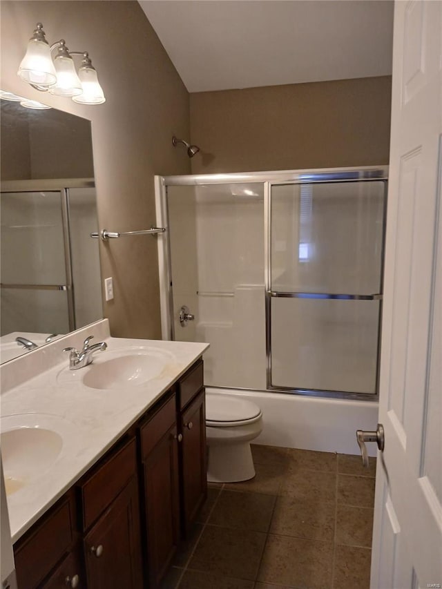 bathroom with double vanity, a sink, tile patterned floors, and toilet