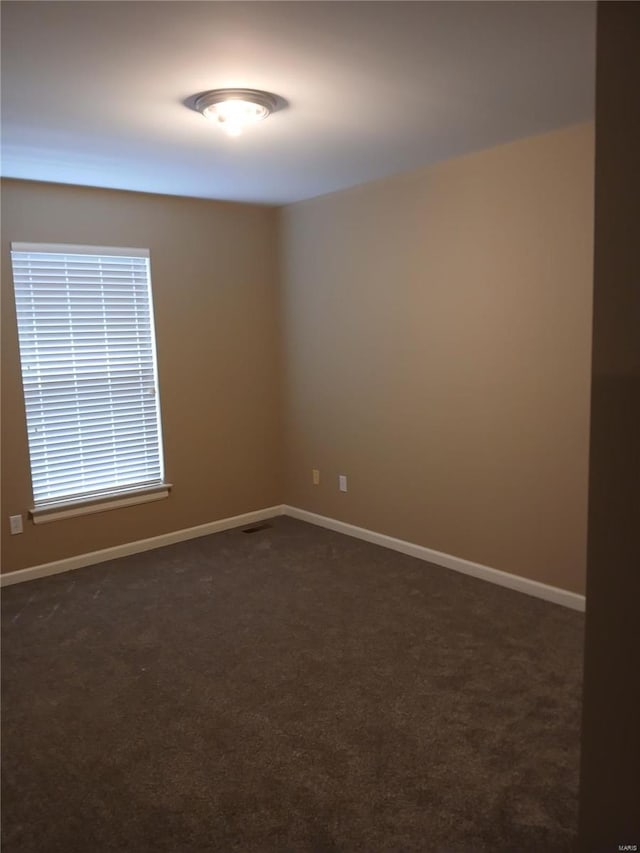 empty room with baseboards, dark colored carpet, and visible vents