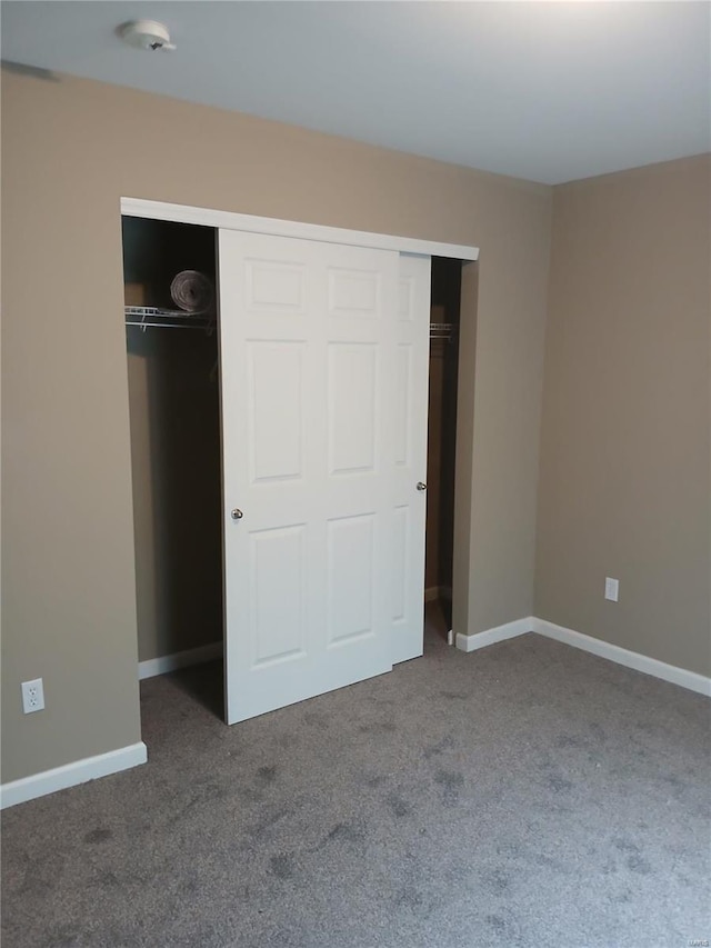 unfurnished bedroom featuring baseboards, carpet, and a closet