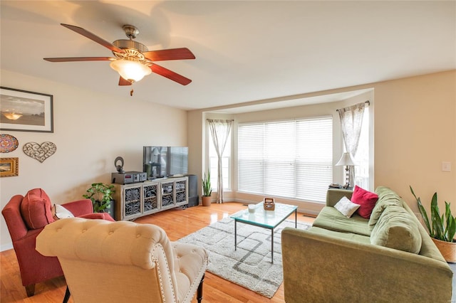 living area with baseboards, ceiling fan, and light wood finished floors