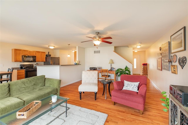 living area featuring baseboards, ceiling fan, light wood-type flooring, and visible vents