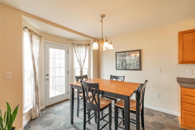 dining space with baseboards, a chandelier, and a healthy amount of sunlight