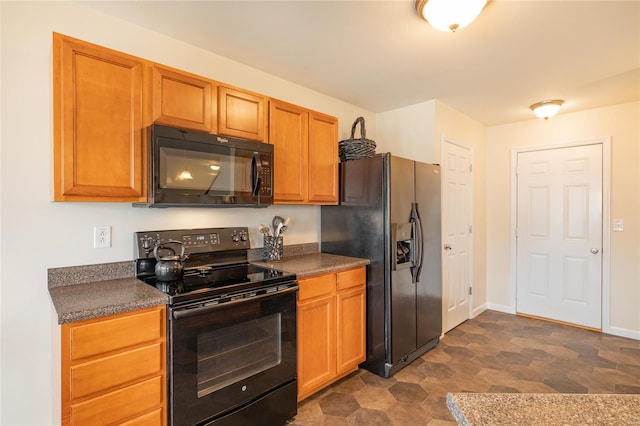 kitchen featuring baseboards, black appliances, and dark countertops