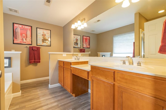 bathroom with visible vents, double vanity, baseboards, and wood finished floors