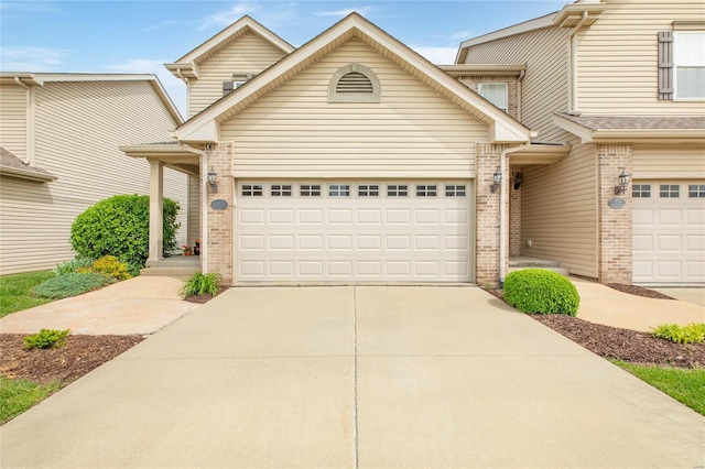 view of property with brick siding, a garage, and concrete driveway