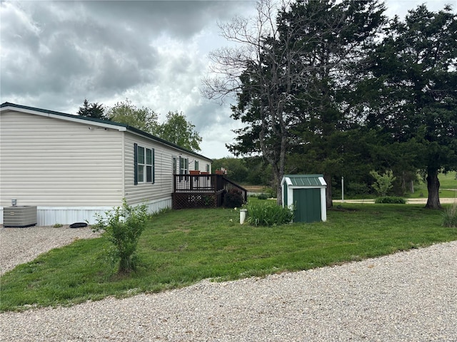 view of property exterior featuring a wooden deck, a shed, an outbuilding, cooling unit, and a lawn