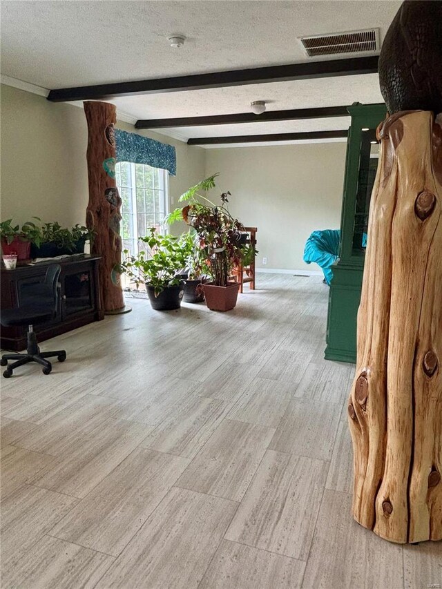 interior space featuring visible vents, a textured ceiling, wood finished floors, and beamed ceiling