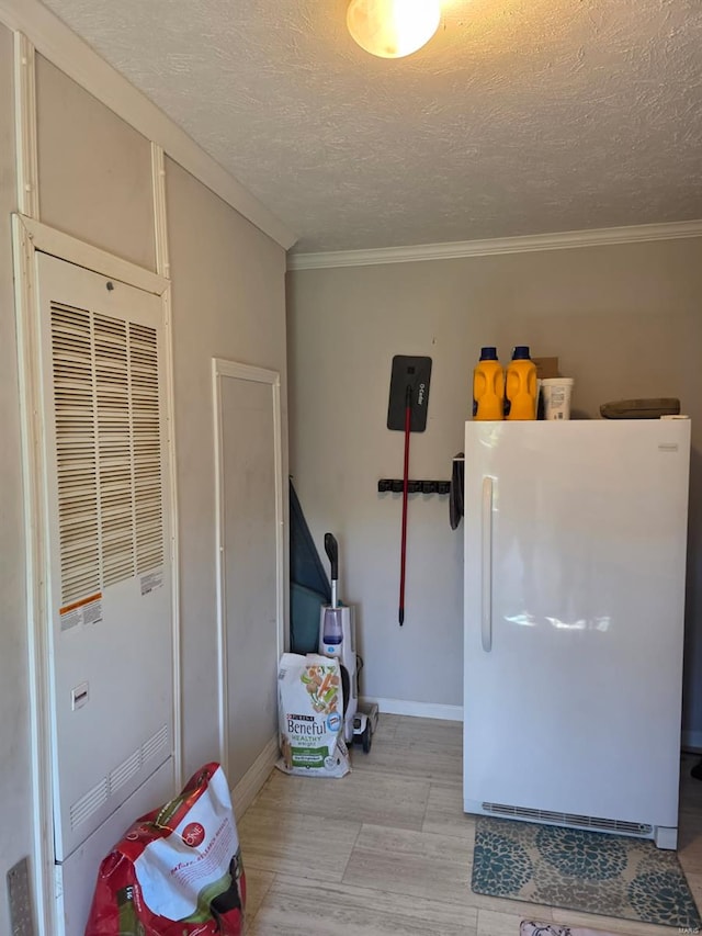 miscellaneous room featuring crown molding, a heating unit, baseboards, a textured ceiling, and light wood-style flooring