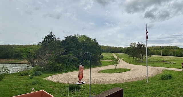 view of community featuring a water view, a yard, and a wooded view