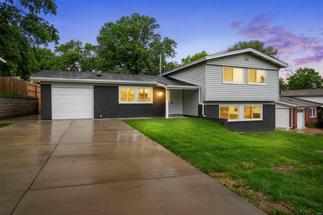 split level home featuring concrete driveway, brick siding, a front yard, and a garage