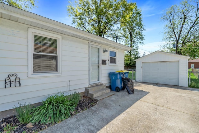 entrance to property featuring a detached garage, fence, and driveway
