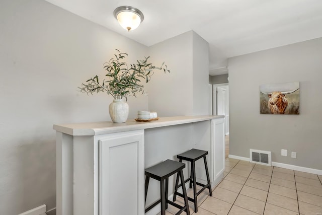 interior space featuring baseboards, light tile patterned flooring, and visible vents