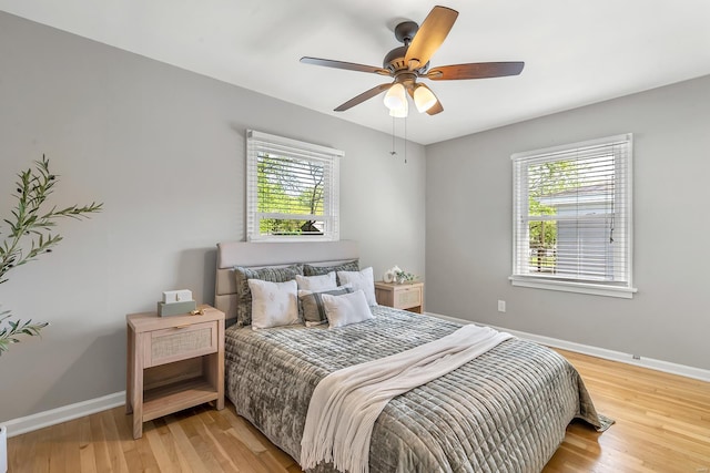 bedroom with baseboards, multiple windows, and light wood-style flooring
