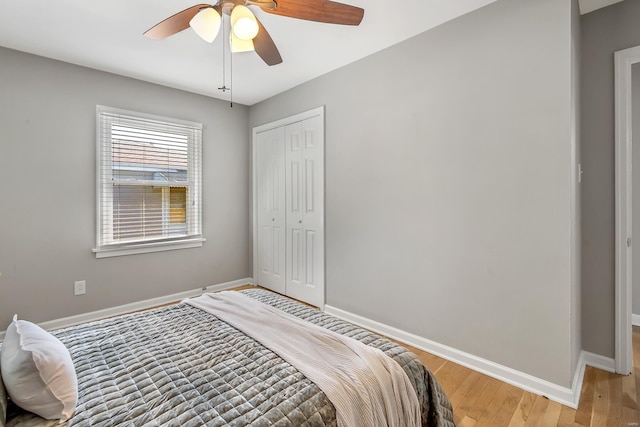 bedroom with baseboards, ceiling fan, light wood finished floors, and a closet