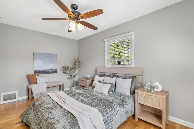 bedroom featuring visible vents, baseboards, ceiling fan, and wood finished floors