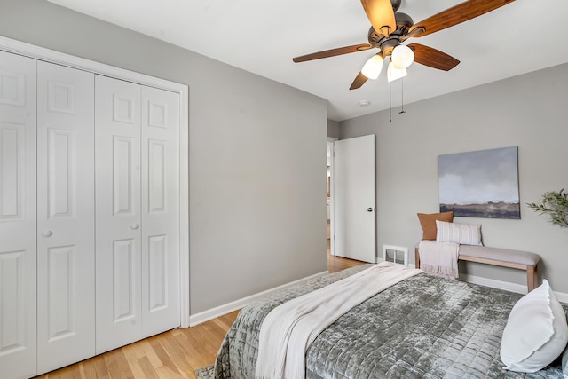 bedroom featuring a ceiling fan, baseboards, light wood-type flooring, visible vents, and a closet