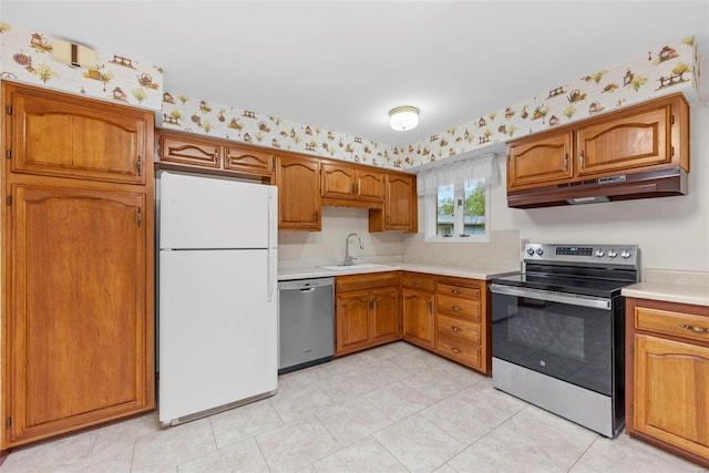 kitchen with appliances with stainless steel finishes, a sink, light countertops, brown cabinetry, and under cabinet range hood