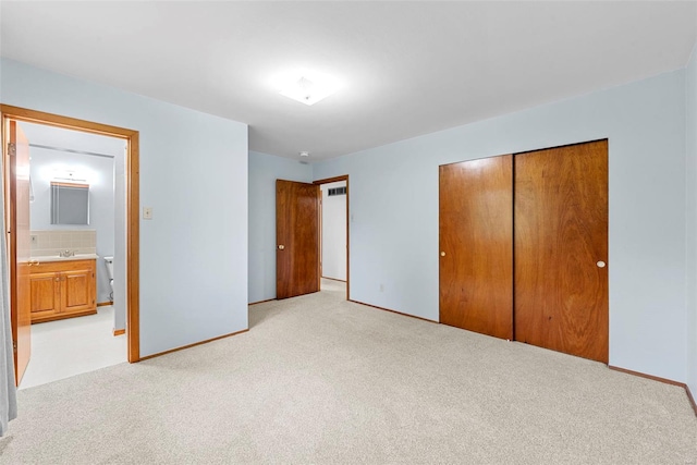 unfurnished bedroom featuring baseboards, light carpet, a sink, and a closet