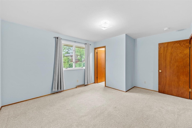 empty room featuring baseboards and light carpet