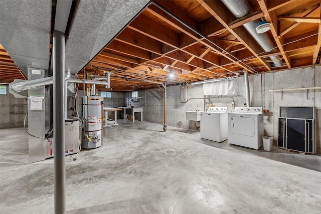 unfinished below grade area with a sink, heating unit, gas water heater, and independent washer and dryer