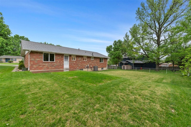 rear view of house featuring brick siding, central air condition unit, fence, and a yard