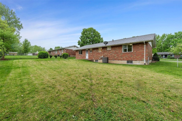 back of property featuring brick siding, a lawn, and fence