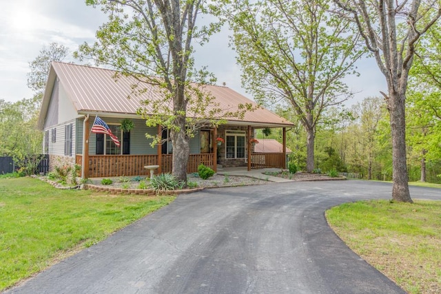 view of front of property with a porch, a front lawn, driveway, and metal roof