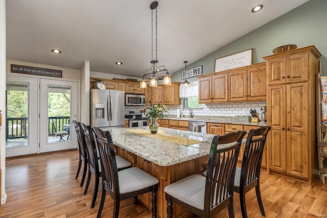 kitchen featuring a sink, appliances with stainless steel finishes, decorative backsplash, and vaulted ceiling