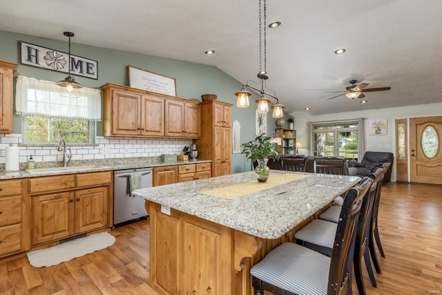 kitchen featuring a sink, light wood-style floors, stainless steel dishwasher, and a center island