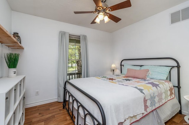bedroom featuring a ceiling fan, visible vents, wood finished floors, baseboards, and access to outside