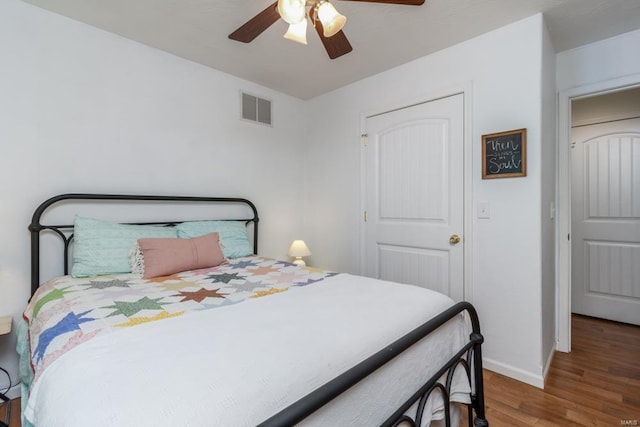 bedroom featuring visible vents, baseboards, ceiling fan, and wood finished floors