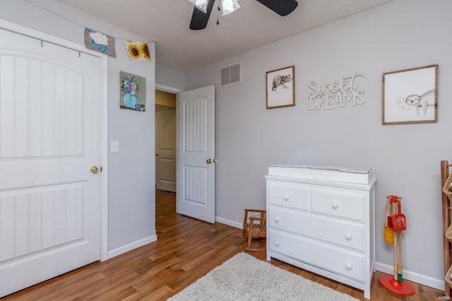 bedroom featuring baseboards, a ceiling fan, wood finished floors, and visible vents