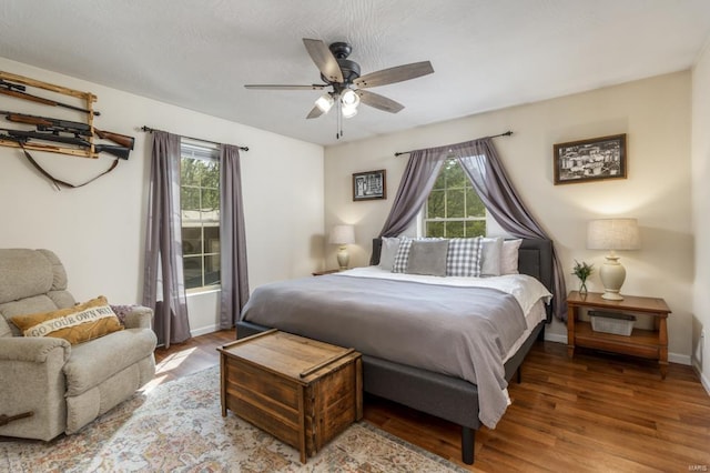 bedroom with baseboards, multiple windows, and wood finished floors