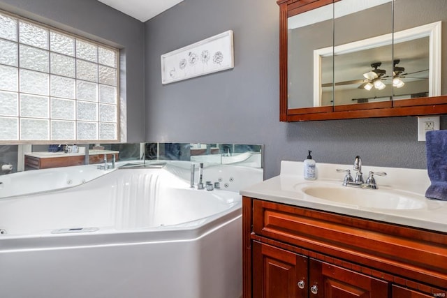 bathroom featuring a whirlpool tub, ceiling fan, and vanity