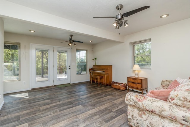 living area with baseboards, ceiling fan, wood finished floors, and a healthy amount of sunlight