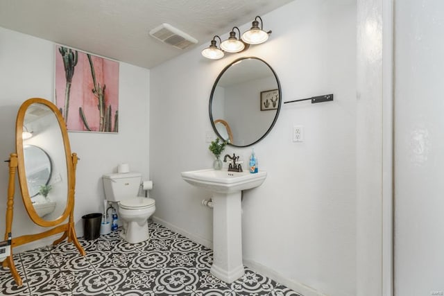 half bathroom featuring toilet, baseboards, and visible vents