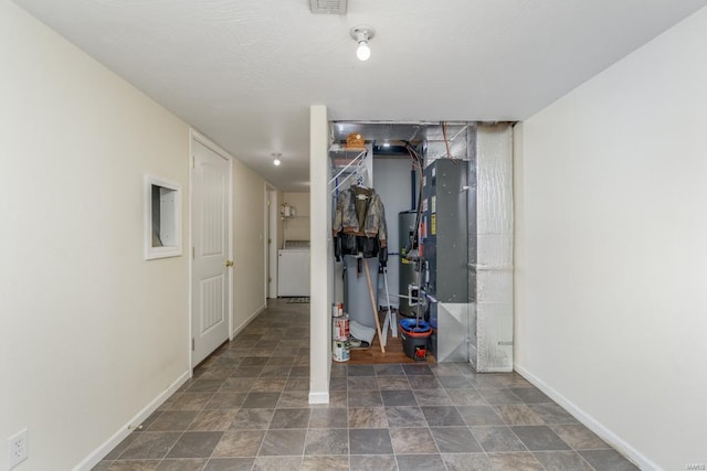 below grade area featuring washer / dryer, baseboards, stone finish floor, and visible vents