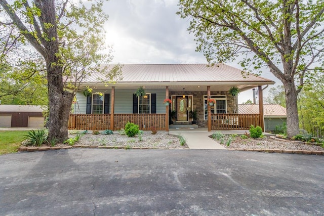 ranch-style home with a detached garage, covered porch, and metal roof