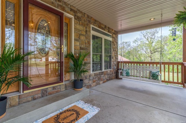 view of exterior entry featuring a porch and stone siding
