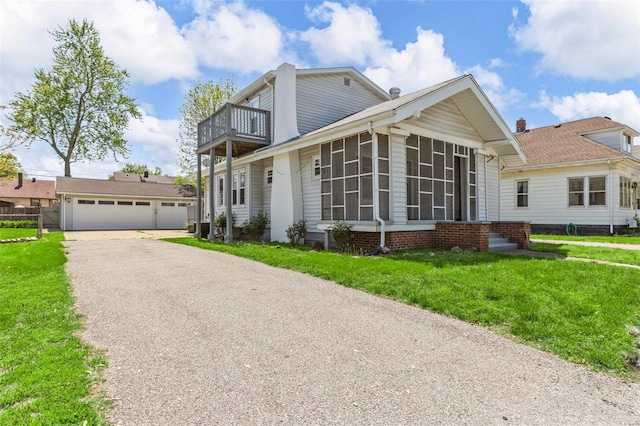 view of front of home featuring a balcony, a front lawn, a sunroom, and a garage