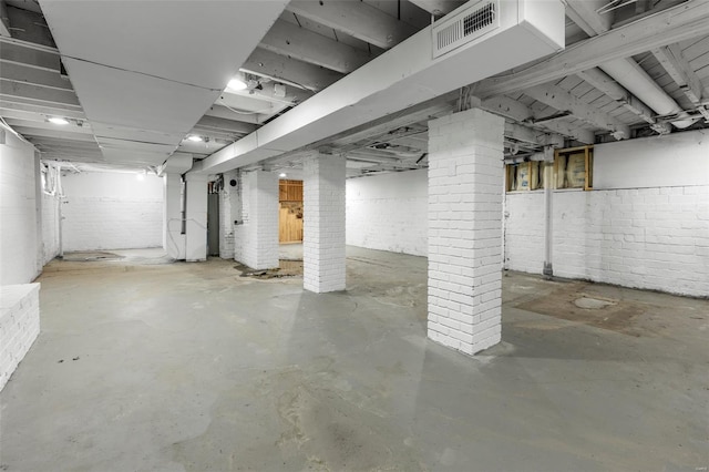 unfinished basement with brick wall and visible vents