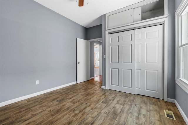 unfurnished bedroom featuring visible vents, a closet, wood finished floors, baseboards, and ceiling fan