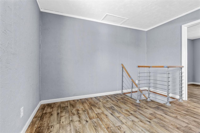 unfurnished room featuring baseboards, a textured wall, wood finished floors, and attic access