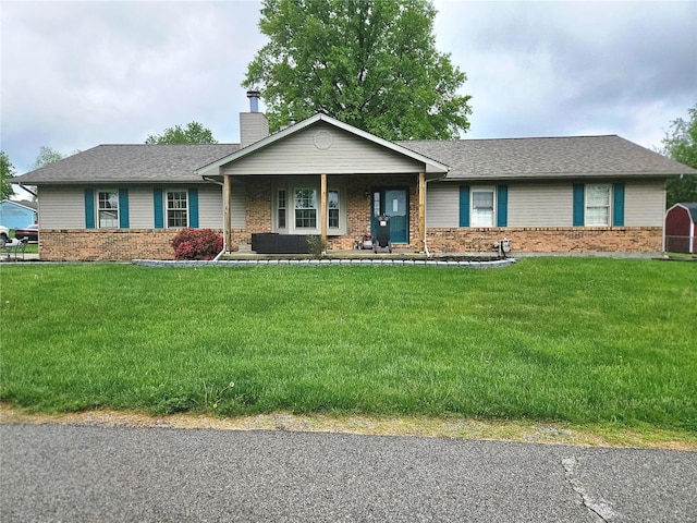 ranch-style house with covered porch, brick siding, a chimney, and a front yard