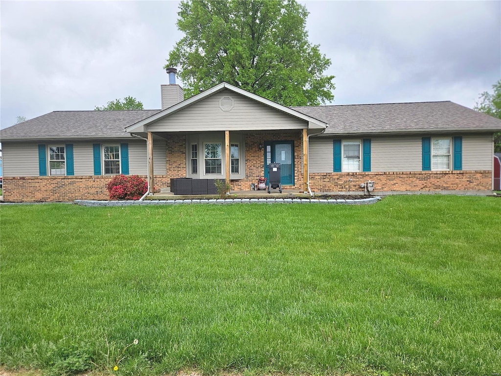 single story home featuring a porch, brick siding, a chimney, and a front lawn