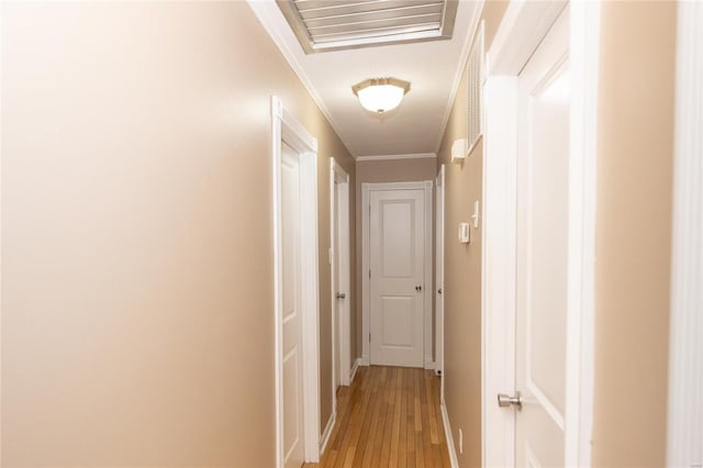 hall featuring visible vents, light wood-style floors, crown molding, and baseboards