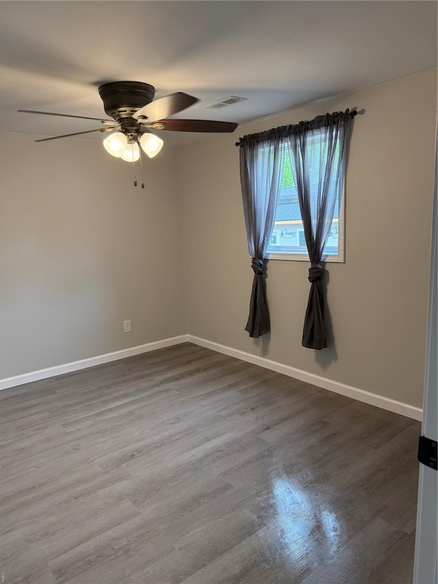 empty room featuring baseboards, ceiling fan, dark wood-style flooring, and visible vents