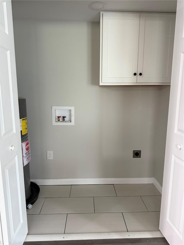 clothes washing area with tile patterned flooring, hookup for a washing machine, electric water heater, electric dryer hookup, and cabinet space